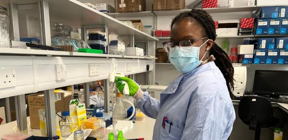 Black female scientist in lab coat and lab glasses