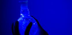 A flask glowing blue in ultra violet light