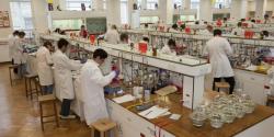 long view of chemistry students in lab coats working in chem teach labs