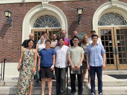 Scientists stand outside a building on the steps.