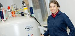 Clare Grey standing next to an NMR machine
