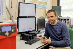 A man sits at a desk with two monitors.