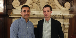 Two men in front of a ornate mantelpiece.