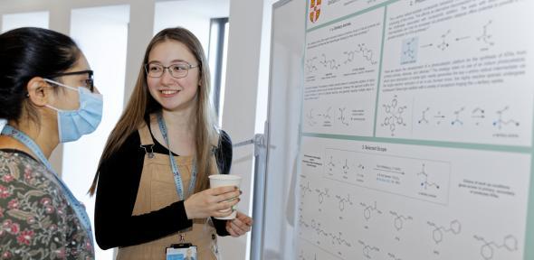 Two women PhD students discussing a chemistry poster