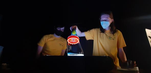 Two volunteers holding a tube filled with bright liquids