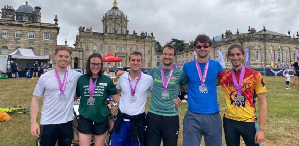 The six team members with arms around each other and Castle Howard in background