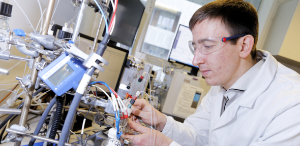 Dr Sam Cobb in lab gear working at a lab instrument