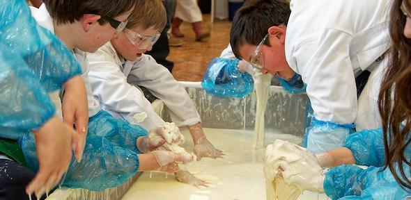 children putting hands in large bucket of slime