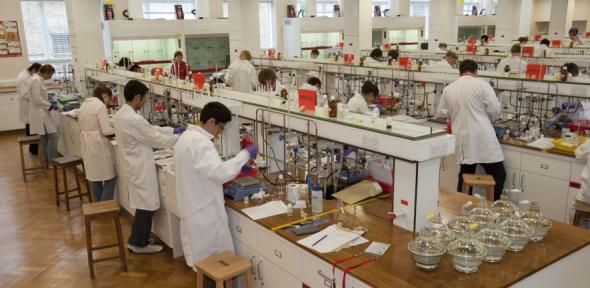 long view of chemistry students in lab coats working in chem teach labs