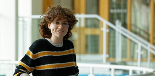 Becky leans against a railing in the department foyer.