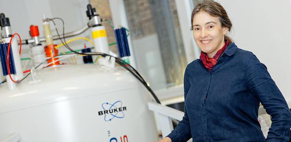Professor Clare Grey standing next to an NMR machine