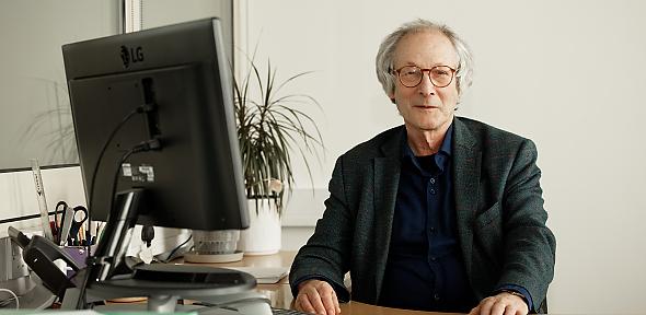 Prof Daan Frenkel sitting by computer smiling at camera