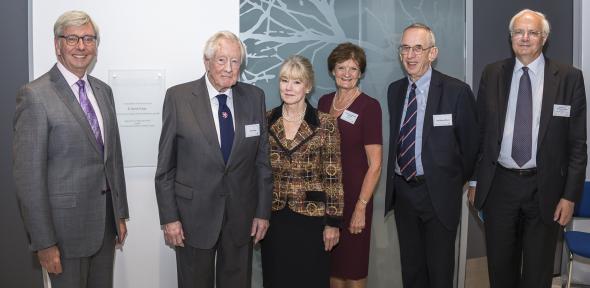 Six people stand in front of a glass plaque