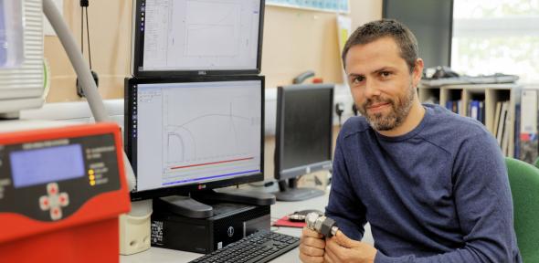 A man sits at a desk with two monitors.