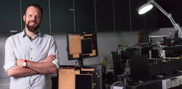 Professor Steven Lee standing next to an optical instrument in his lab