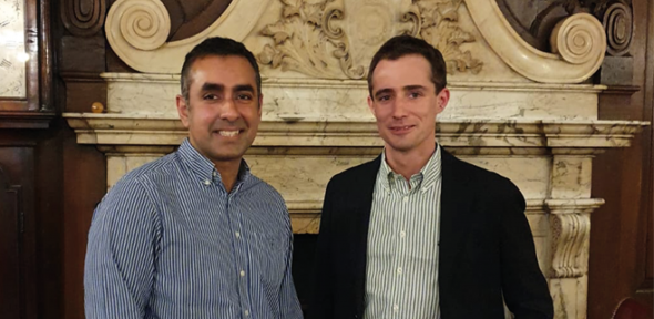 Two men in front of a ornate mantelpiece.