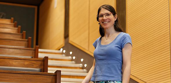 A woman stands in front of lecture theatre seating