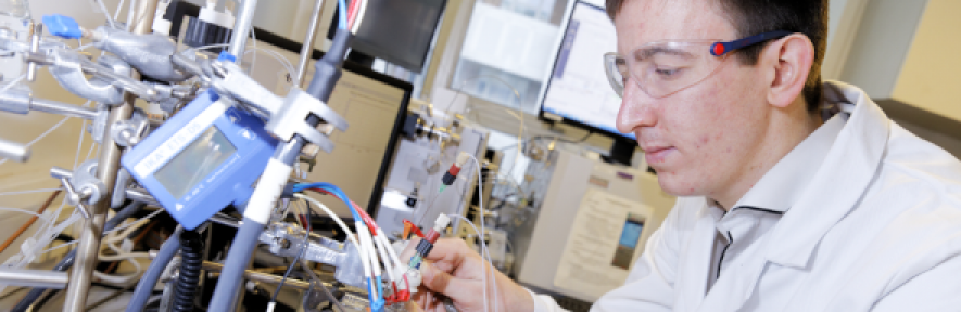 Dr Sam Cobb in lab gear working at a lab instrument