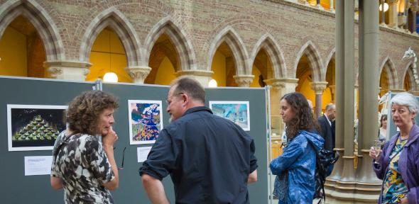 Caroline's painting hanging at the exhibition in large hall with people