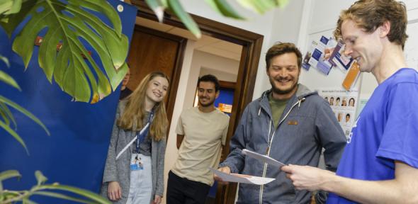 Alex with three students in his office admiring plants