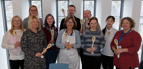Bake Off contestants holding their prize wooden spoons.