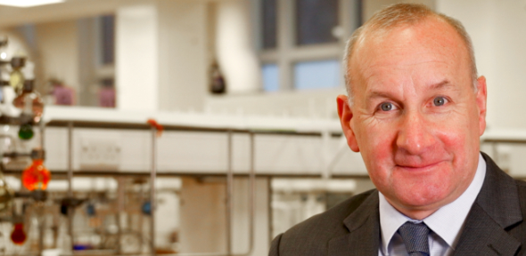 Head of Department Dr James Keeler sitting in front of a chemistry-style Christmas tree