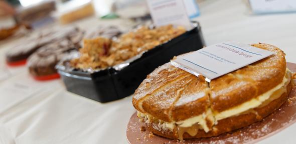 a selection of cakes sitting on a white table-cloth covered table