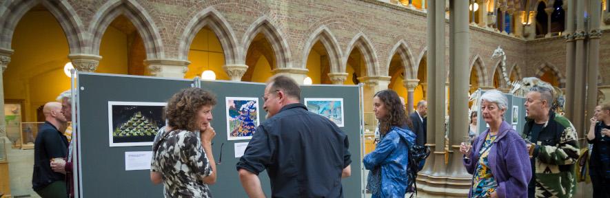 Caroline's painting hanging at the exhibition in large hall with people