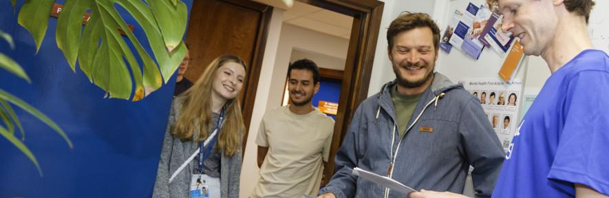 Alex with three students in his office admiring plants