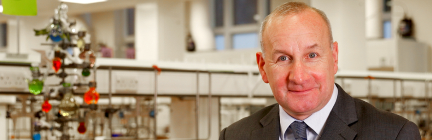 Head of Department Dr James Keeler sitting in front of a chemistry-style Christmas tree